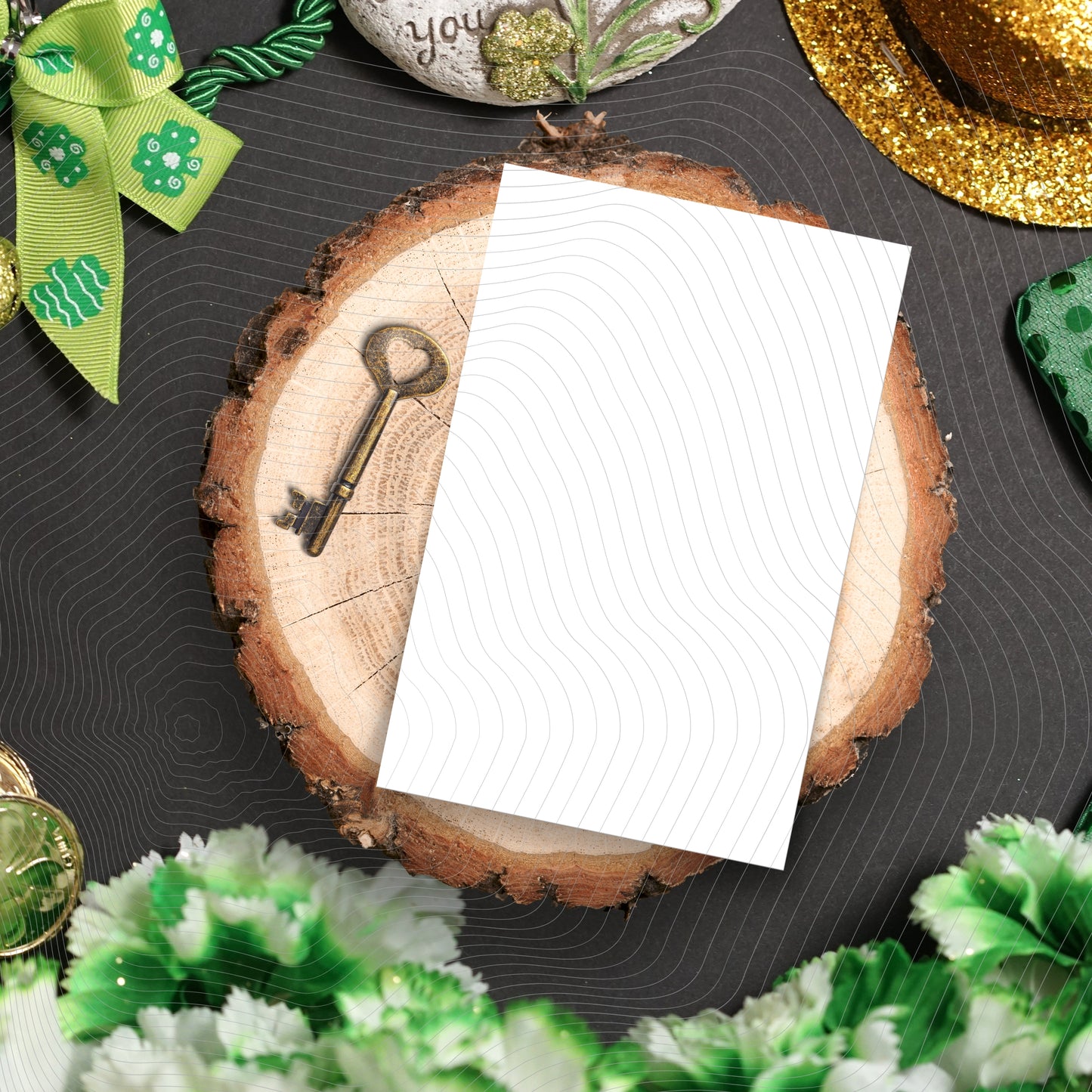 White card on a wooden slice with decorative items including a key and green ribbons.