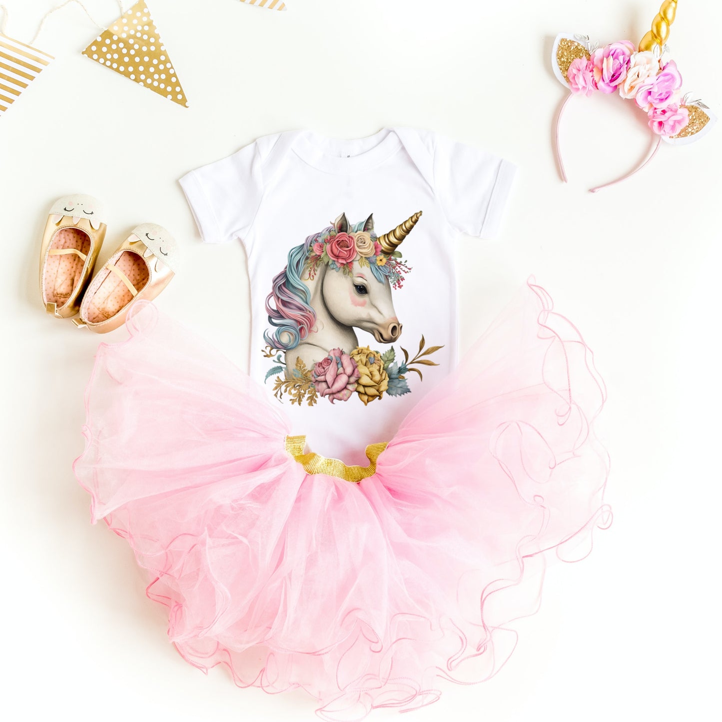 Baby outfit with unicorn design, pink tutu, and floral headband on a white background
