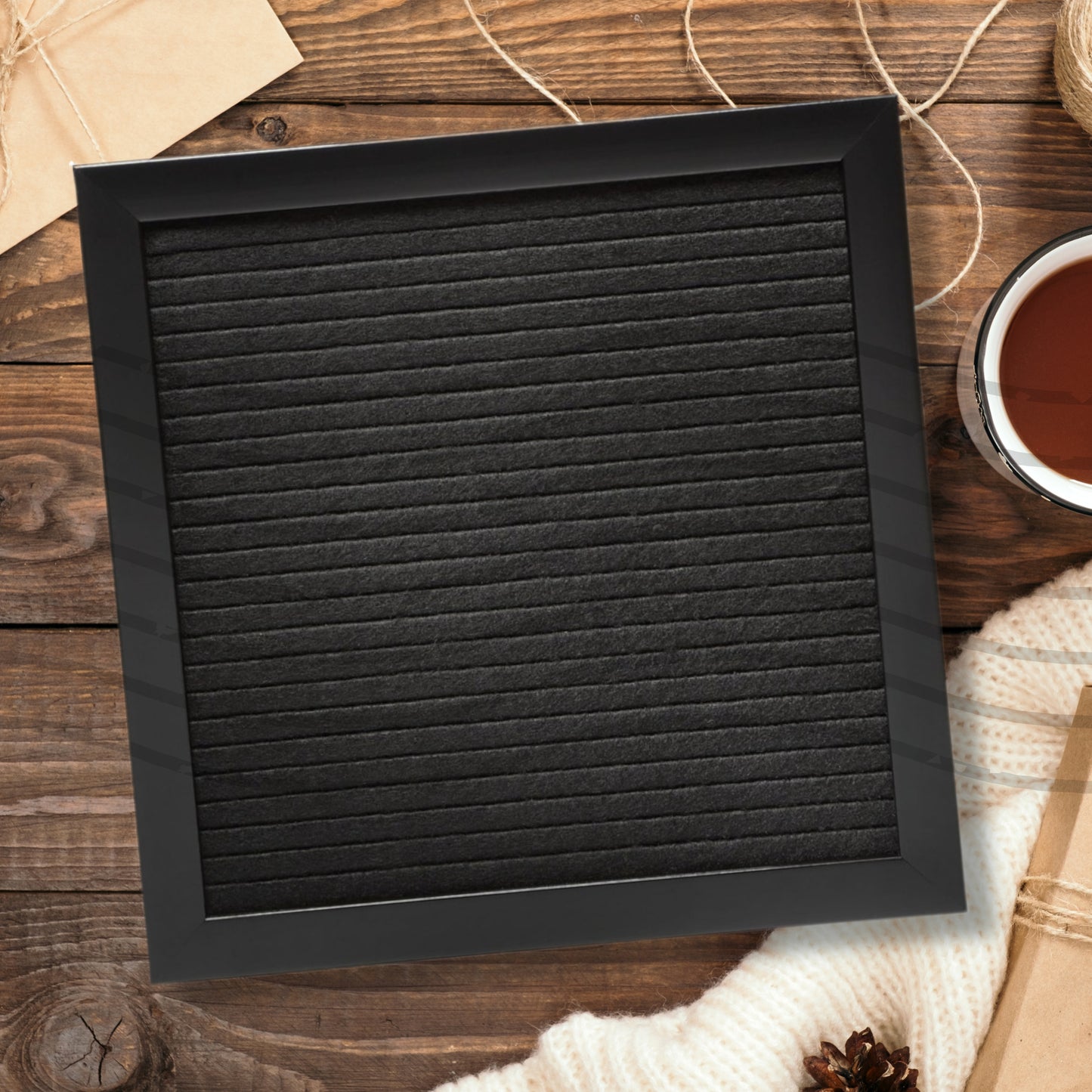 Black framed letterboard on a wooden surface with a cup of tea and yarn.