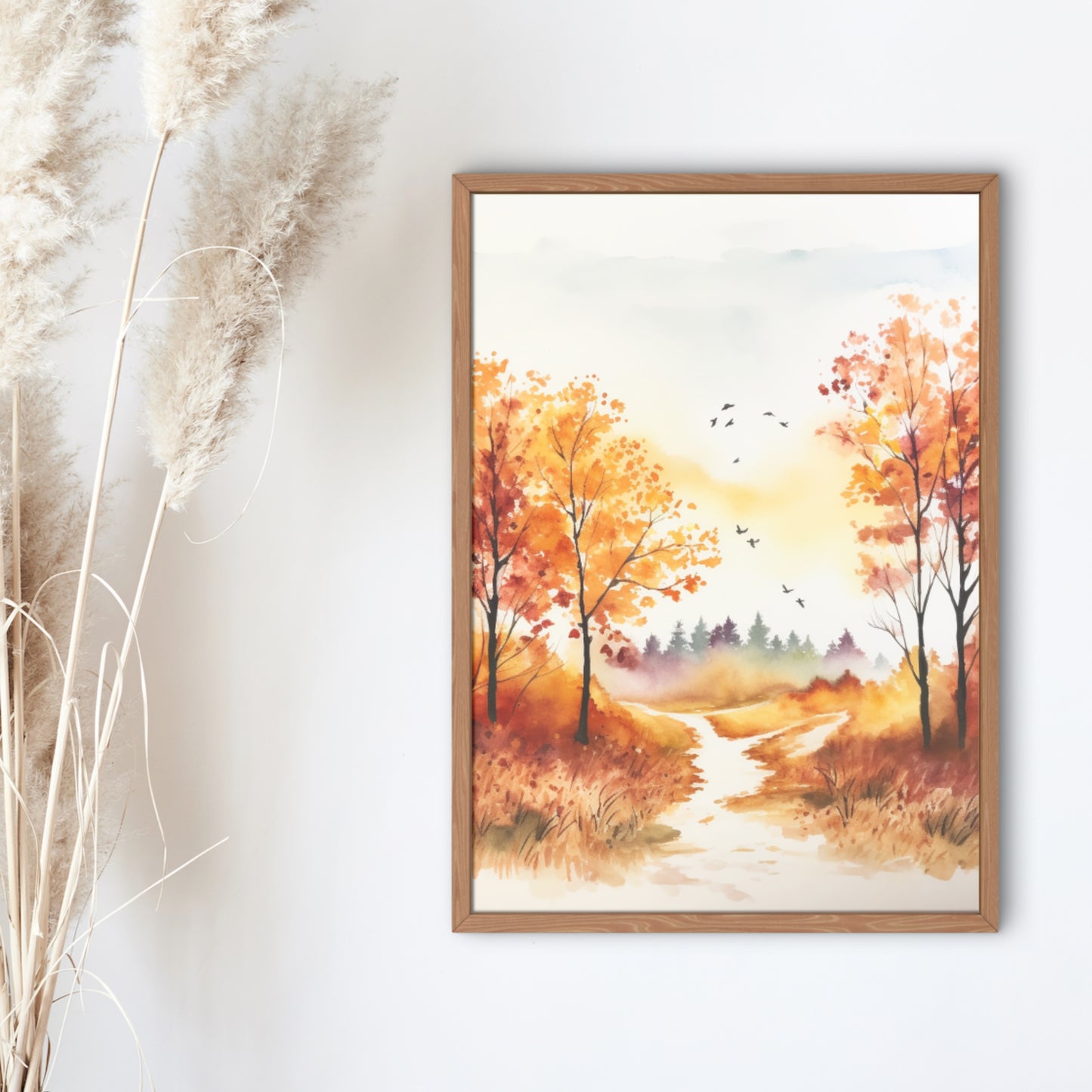 Framed artwork of an autumn landscape with trees and a path on a white wall.