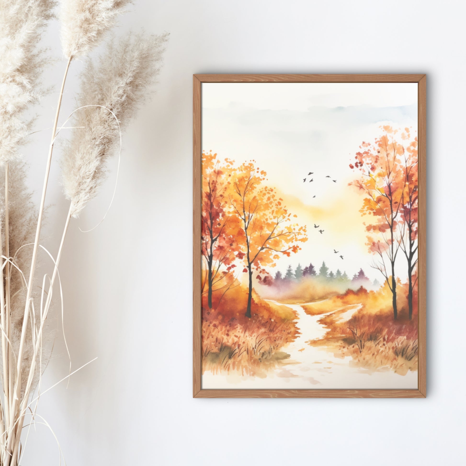 Framed artwork of an autumn landscape with trees and a path on a white wall.
