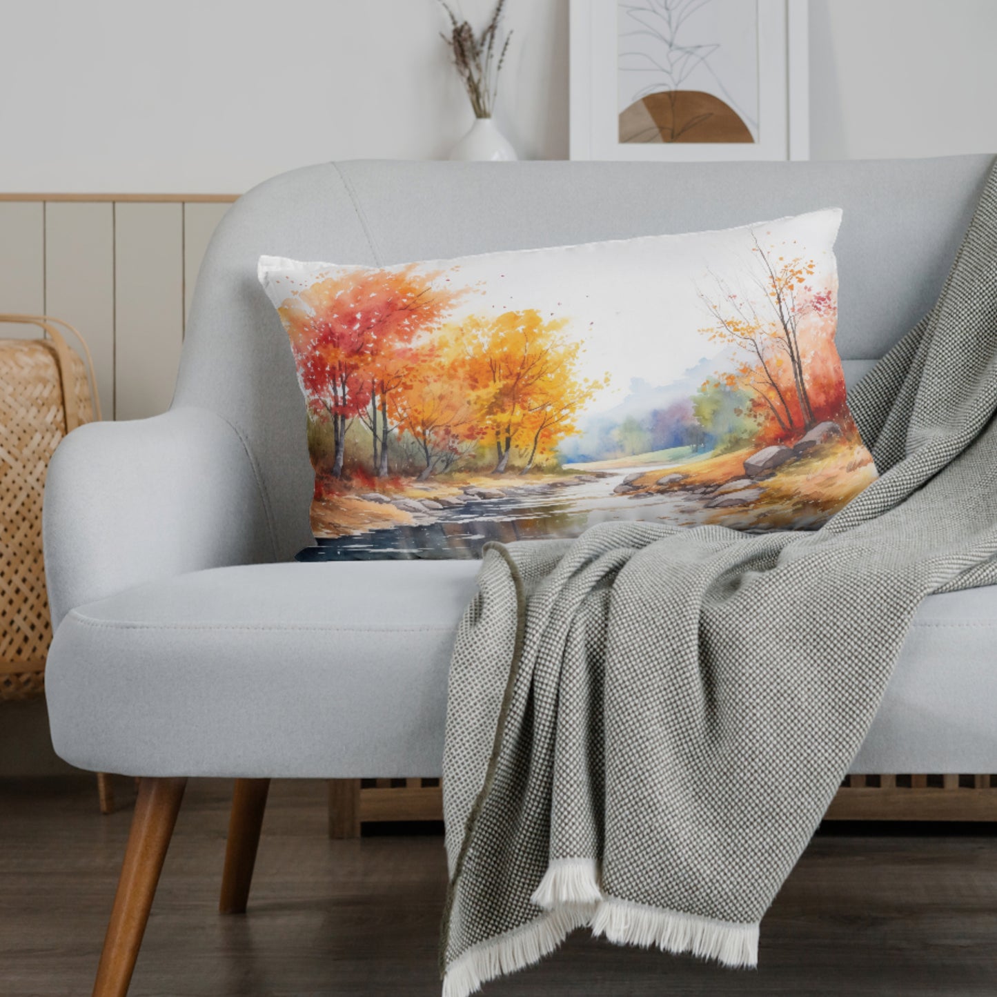 Decorative pillow with autumn landscape on a gray sofa with a blanket