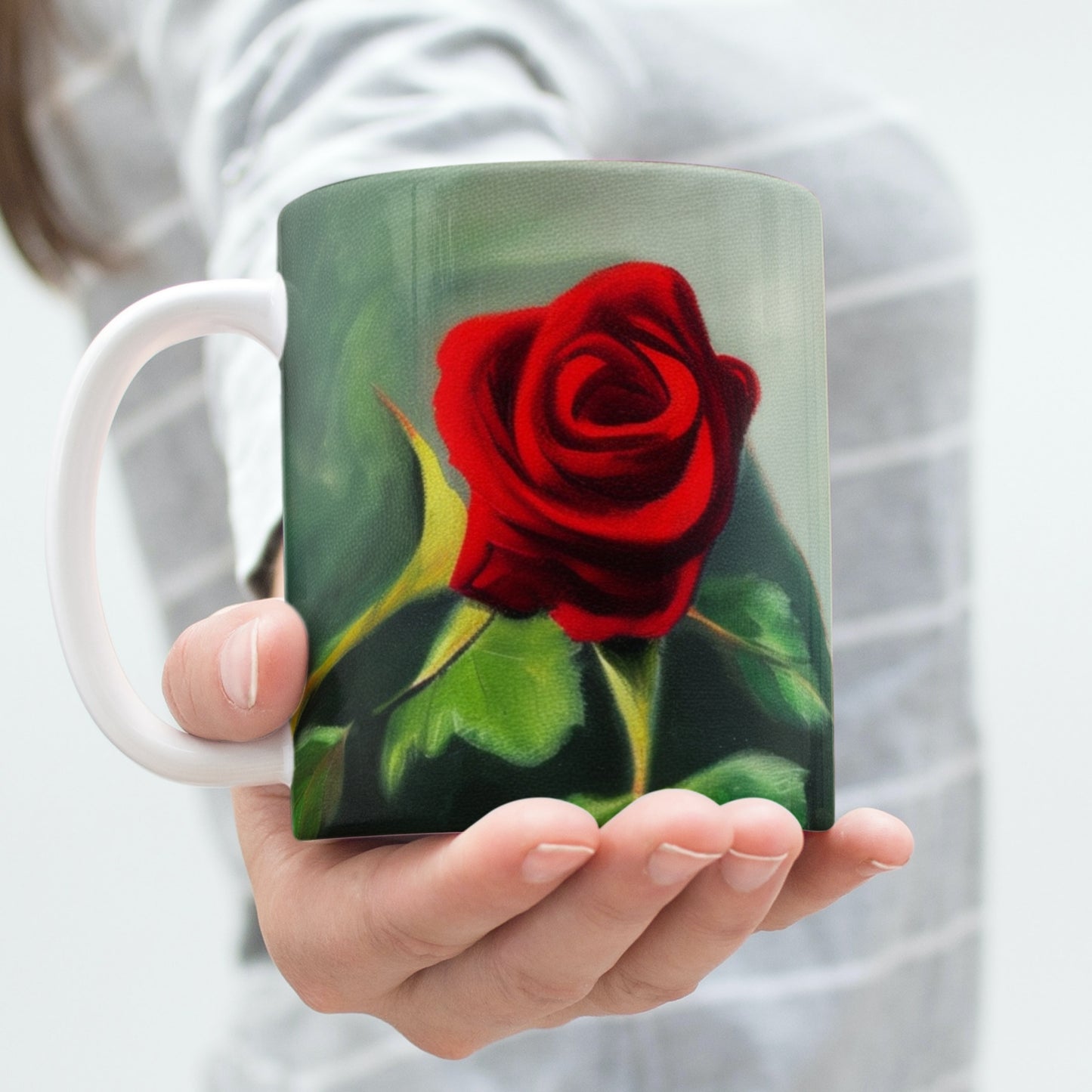 Person holding a mug with a red rose design