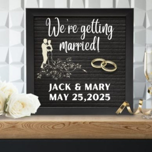 Black letter board with 'We're getting married!' and personalized details on a decorative surface.